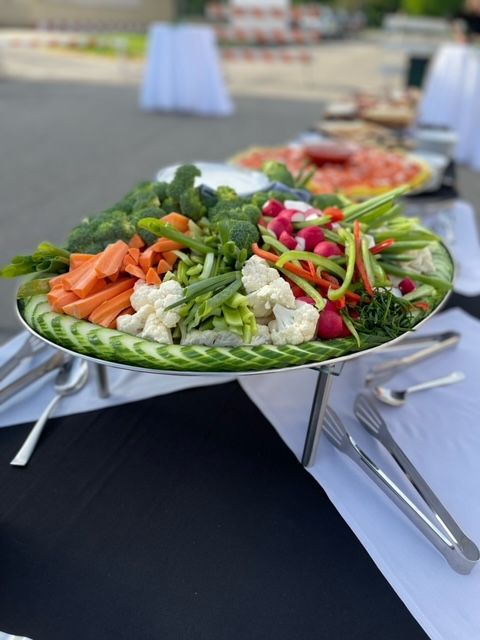 A plate of vegetables on a table with tongs.