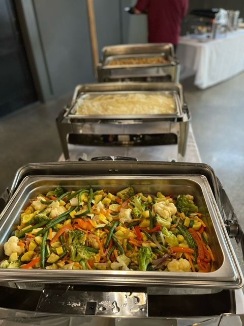 A tray of vegetables is sitting on top of a buffet table.