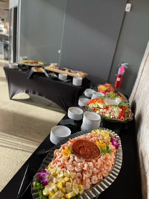 A buffet table with a plate of shrimp and a salad on it.