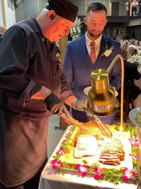 A man in a suit is cutting a piece of meat on a table