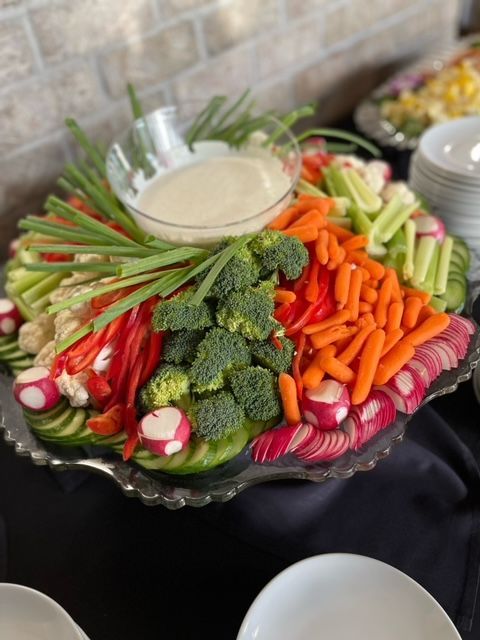 A variety of vegetables on a plate with a dipping sauce