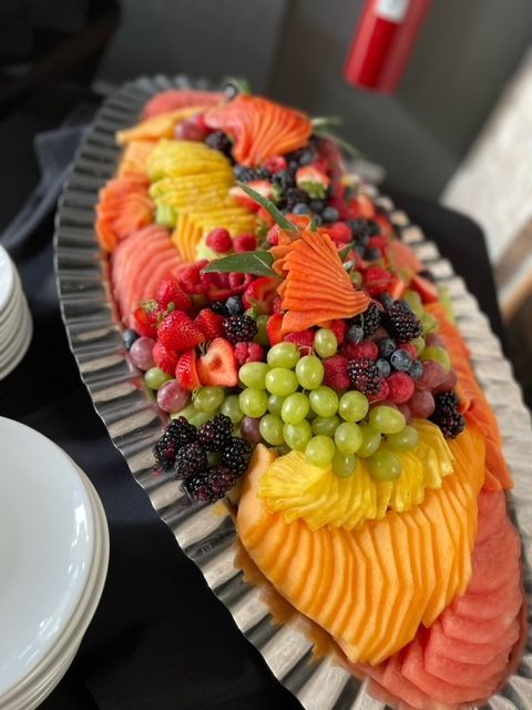 A tray of sliced fruit and berries on a table