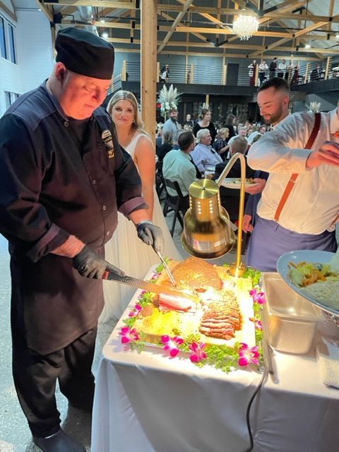 A man in a chef 's uniform is cutting a cake