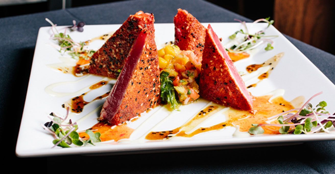A white plate topped with meat and vegetables on a table.
