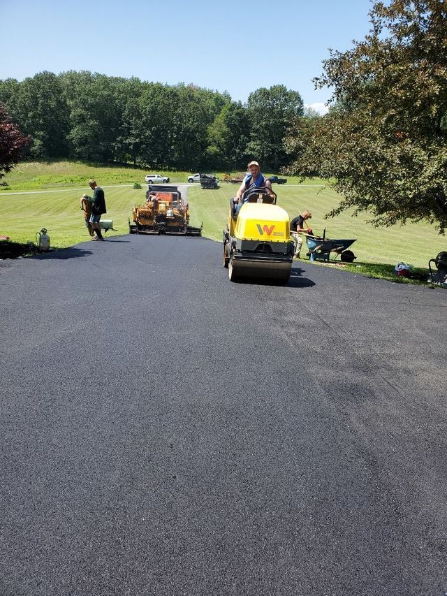 A man is driving a yellow roller on a road