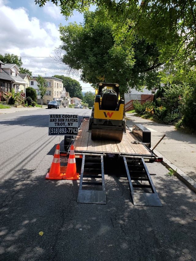 A yellow tractor is parked on a trailer on the side of the road