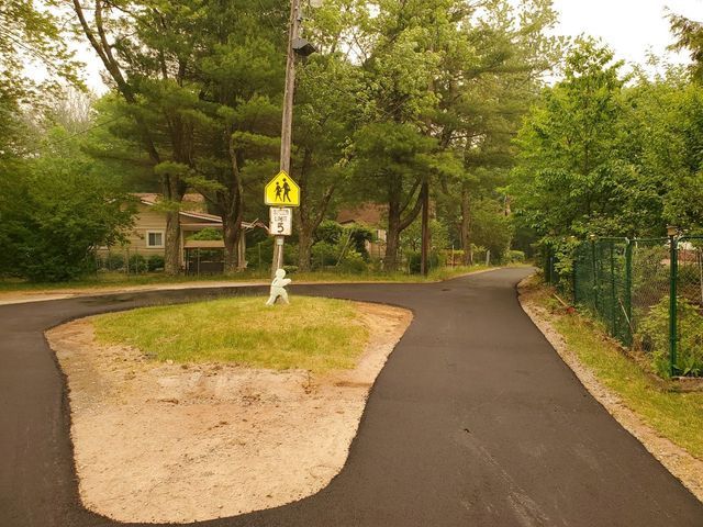 A pedestrian crossing sign is on a pole in the middle of a road