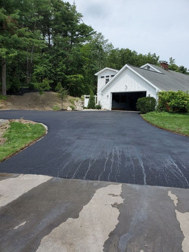 A white house with a black driveway leading to it