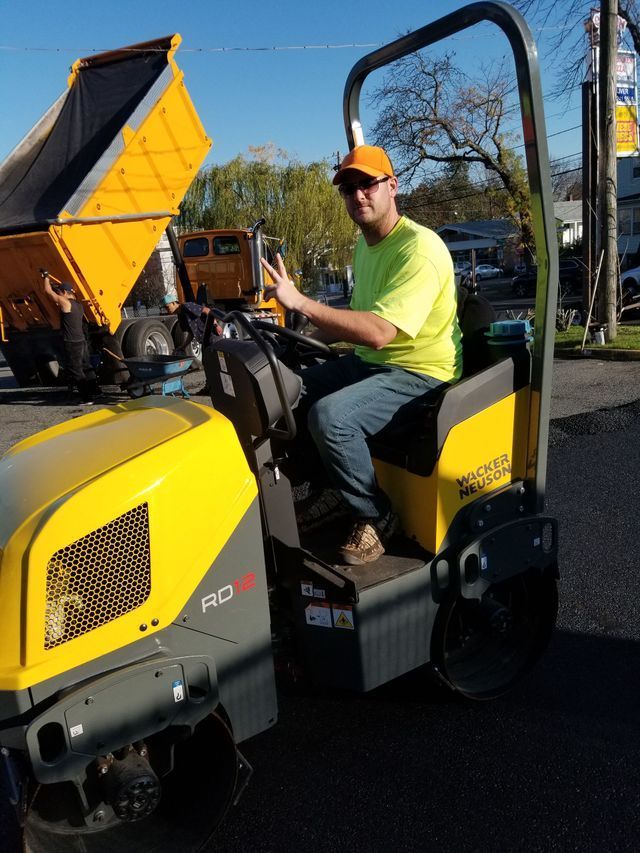 A man in a yellow shirt is driving a yellow roller