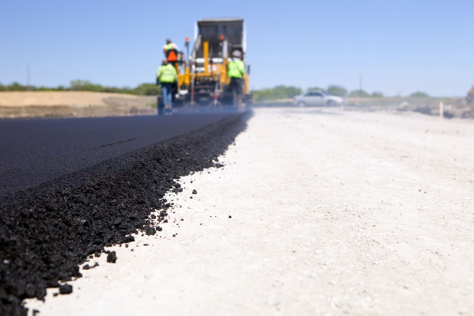 A group of construction workers are laying asphalt on a road.
