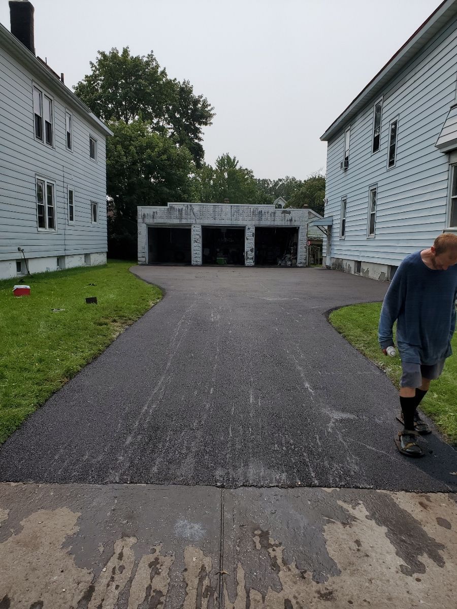 A man is walking down a driveway between two buildings