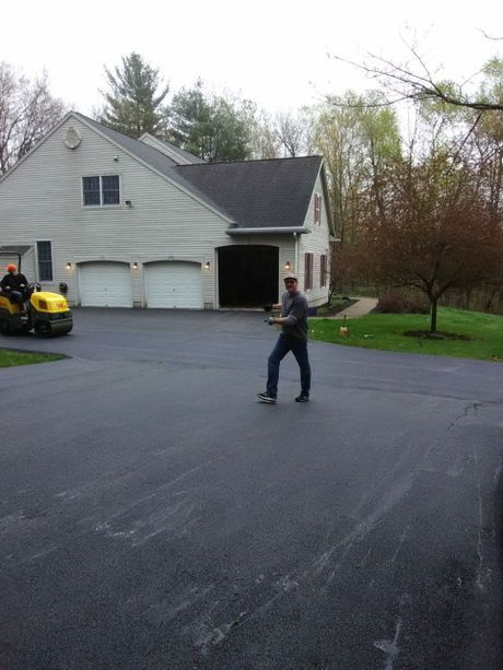 A man is walking down a driveway in front of a house