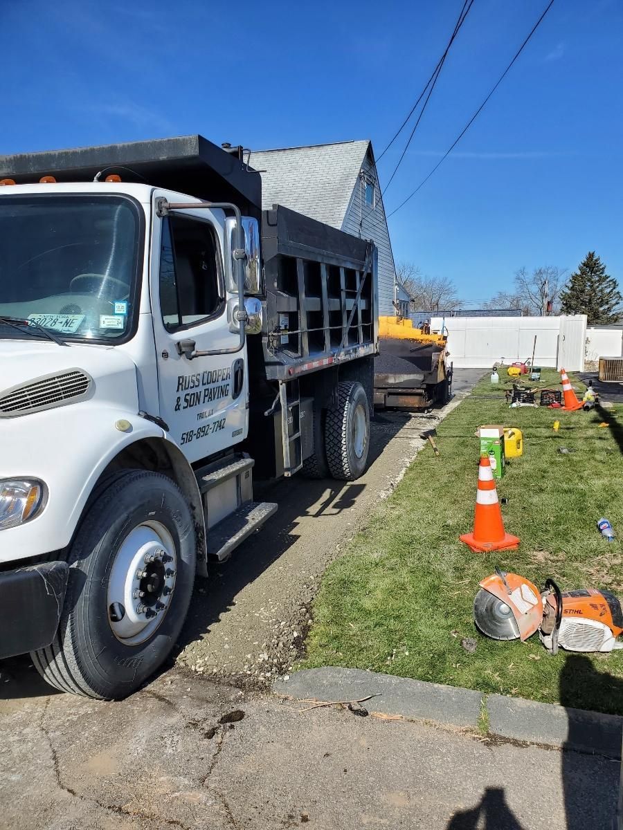 A white dump truck is parked on the side of the road.