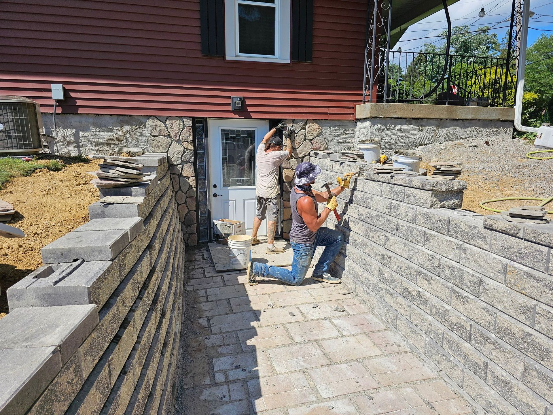 Two people constructing a retaining wall and walkway entrance to a home.