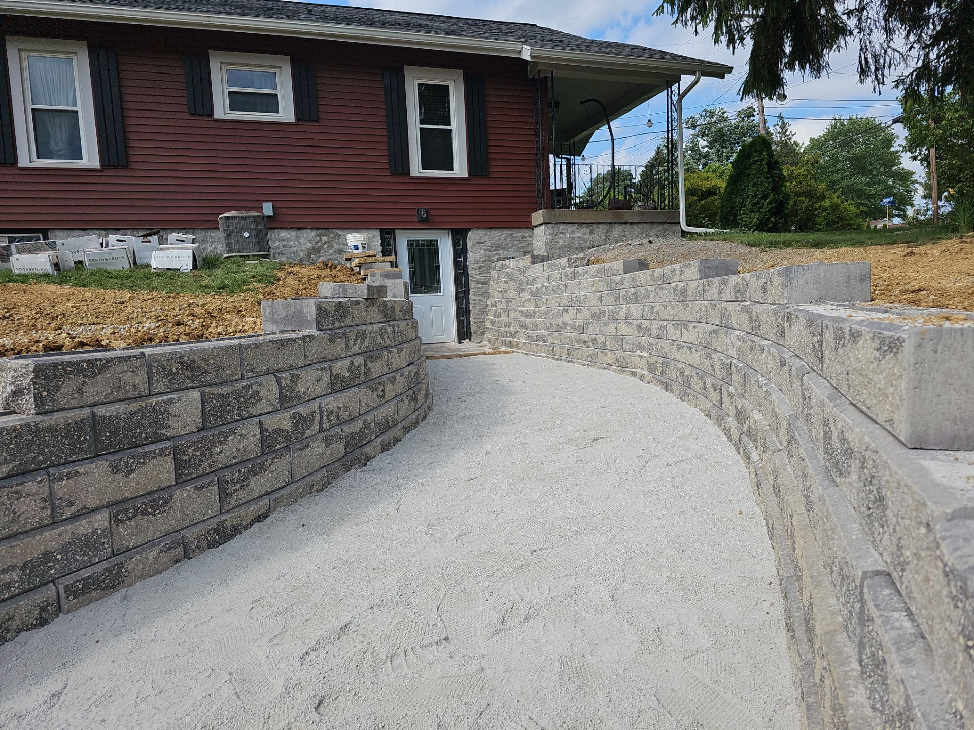 Red house with stone retaining walls surrounding a gravel pathway.