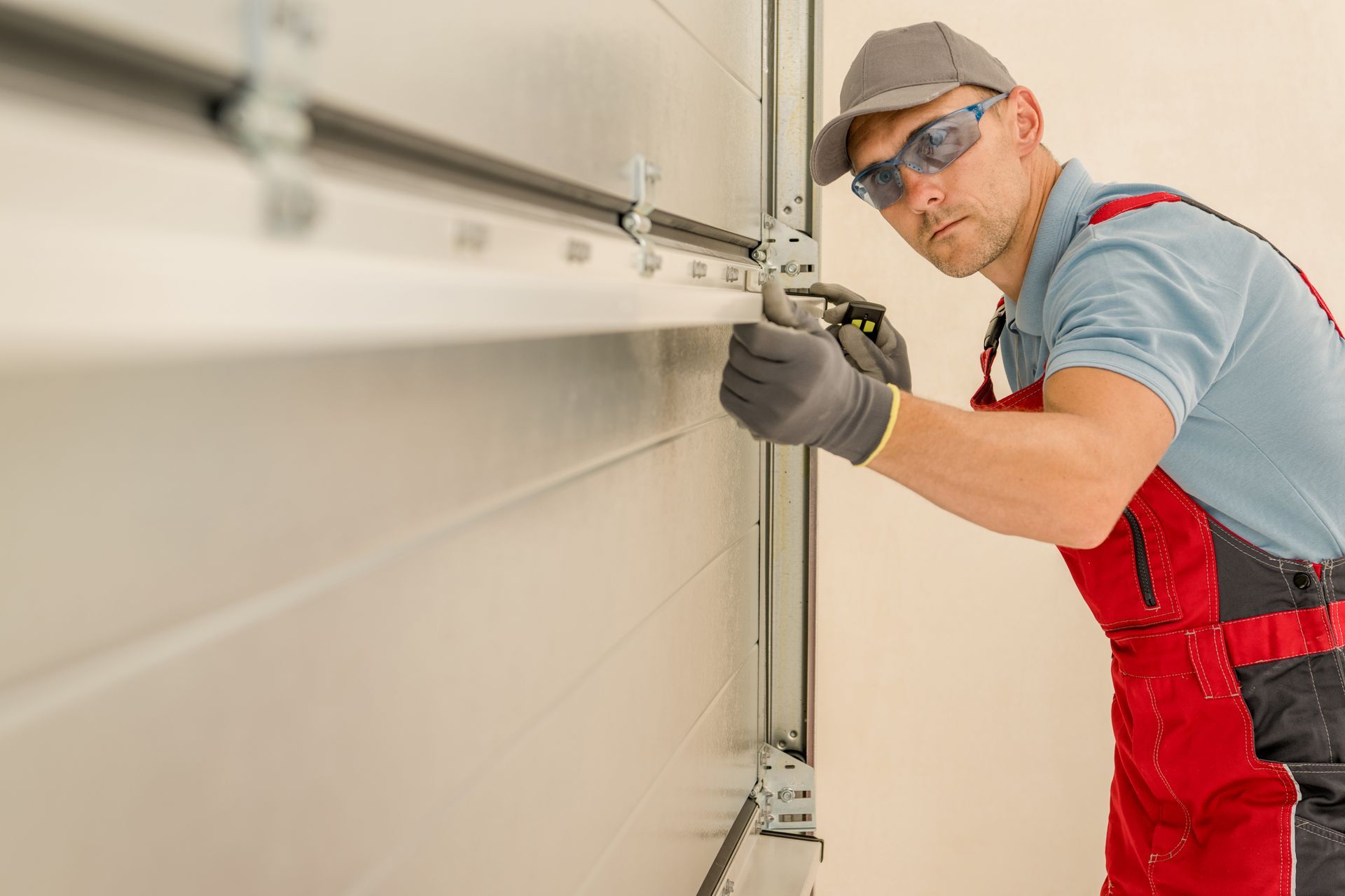 Professional garage door technician installing metal sectional garage door with tools. Professional garage door technician installing metal sectional garage door with tools.