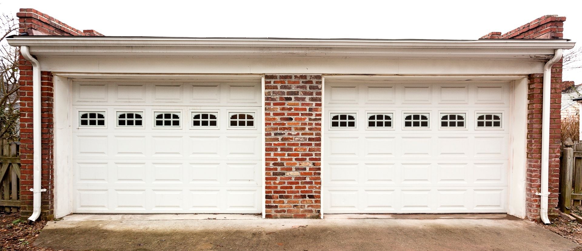 Two white garage doors with brick accents.