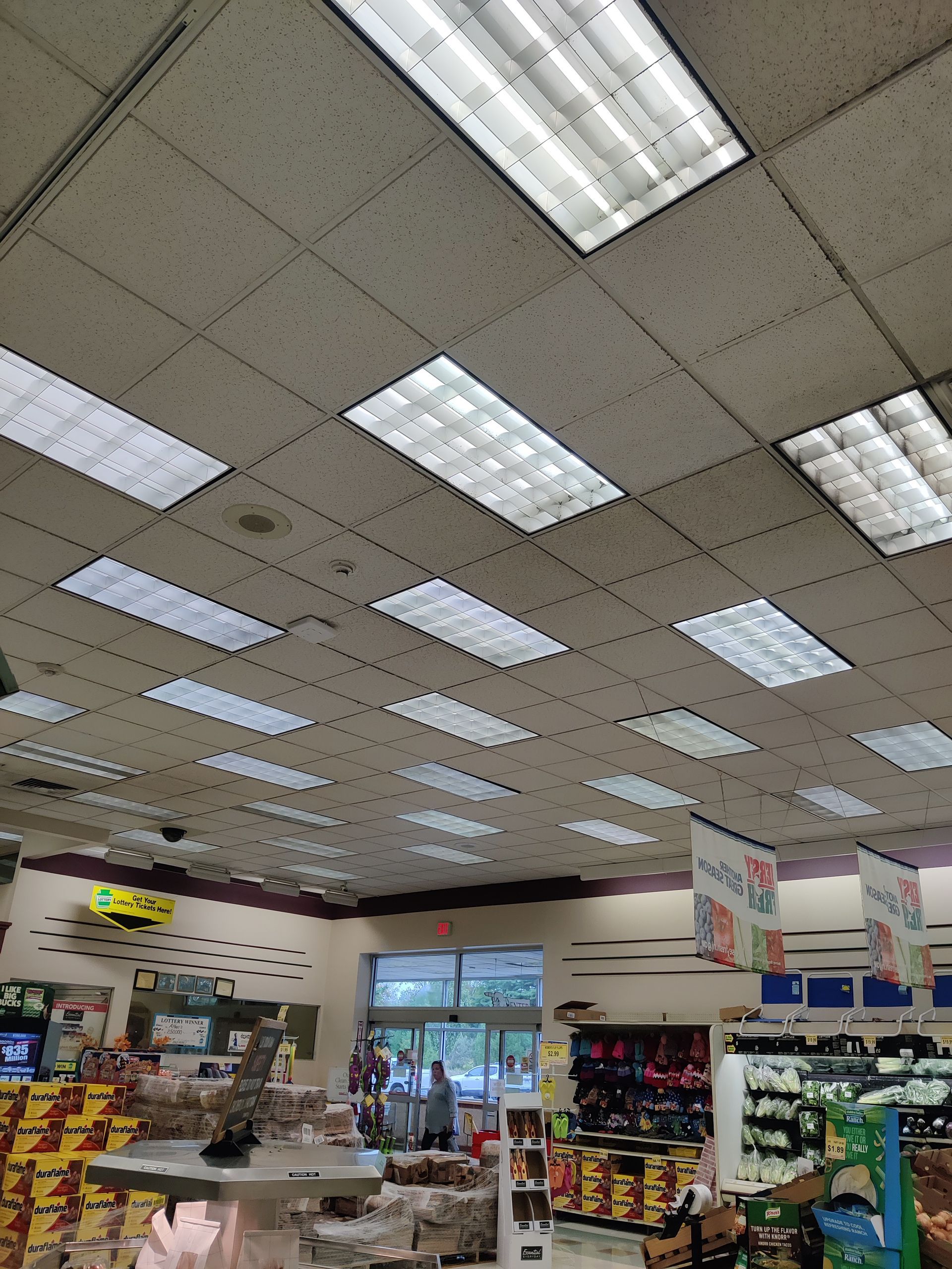 Convenience store interior with bright fluorescent lights, shelves of snacks, and a glass door at the back.