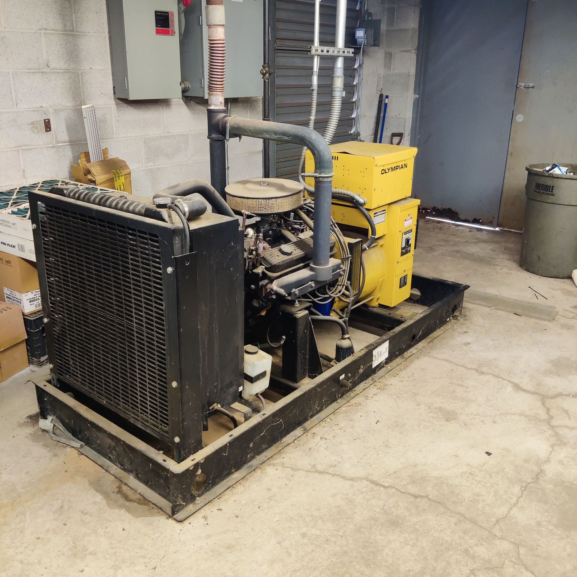 Industrial generator set with black radiator and yellow engine on a concrete floor in a utility room