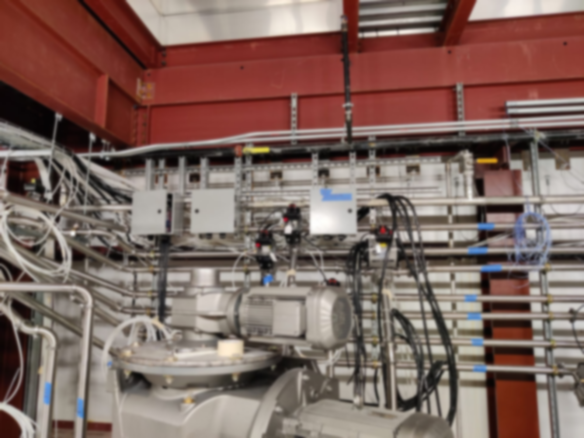 Industrial machinery with cables and pipes in a red-walled factory interior