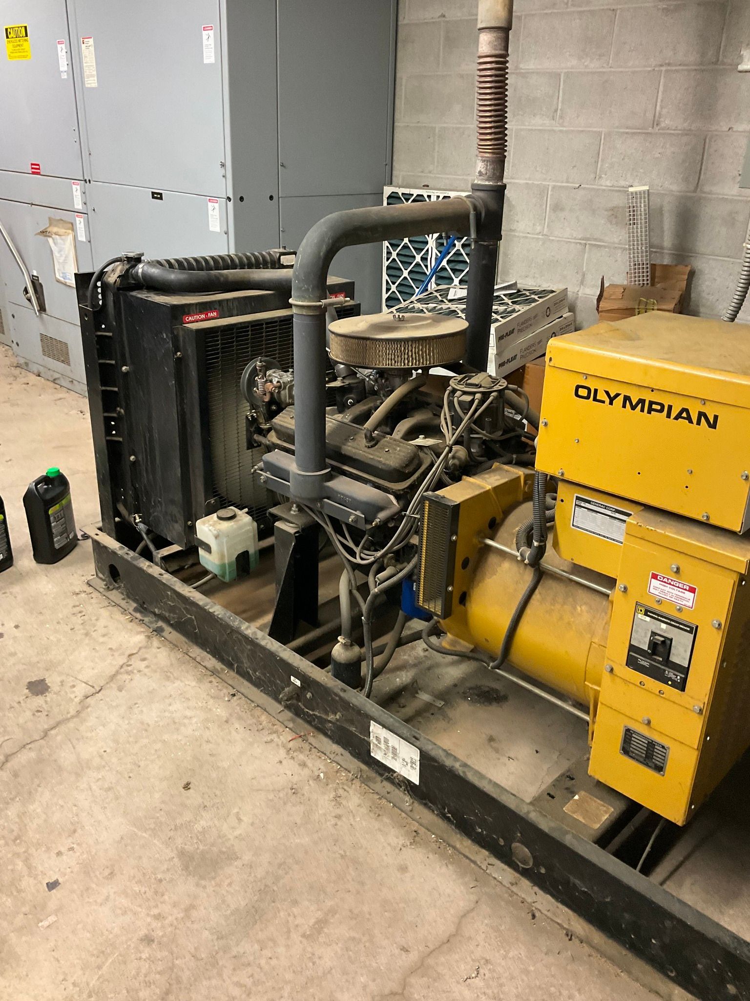 Yellow Olympian generator and black industrial equipment in a concrete utility room
