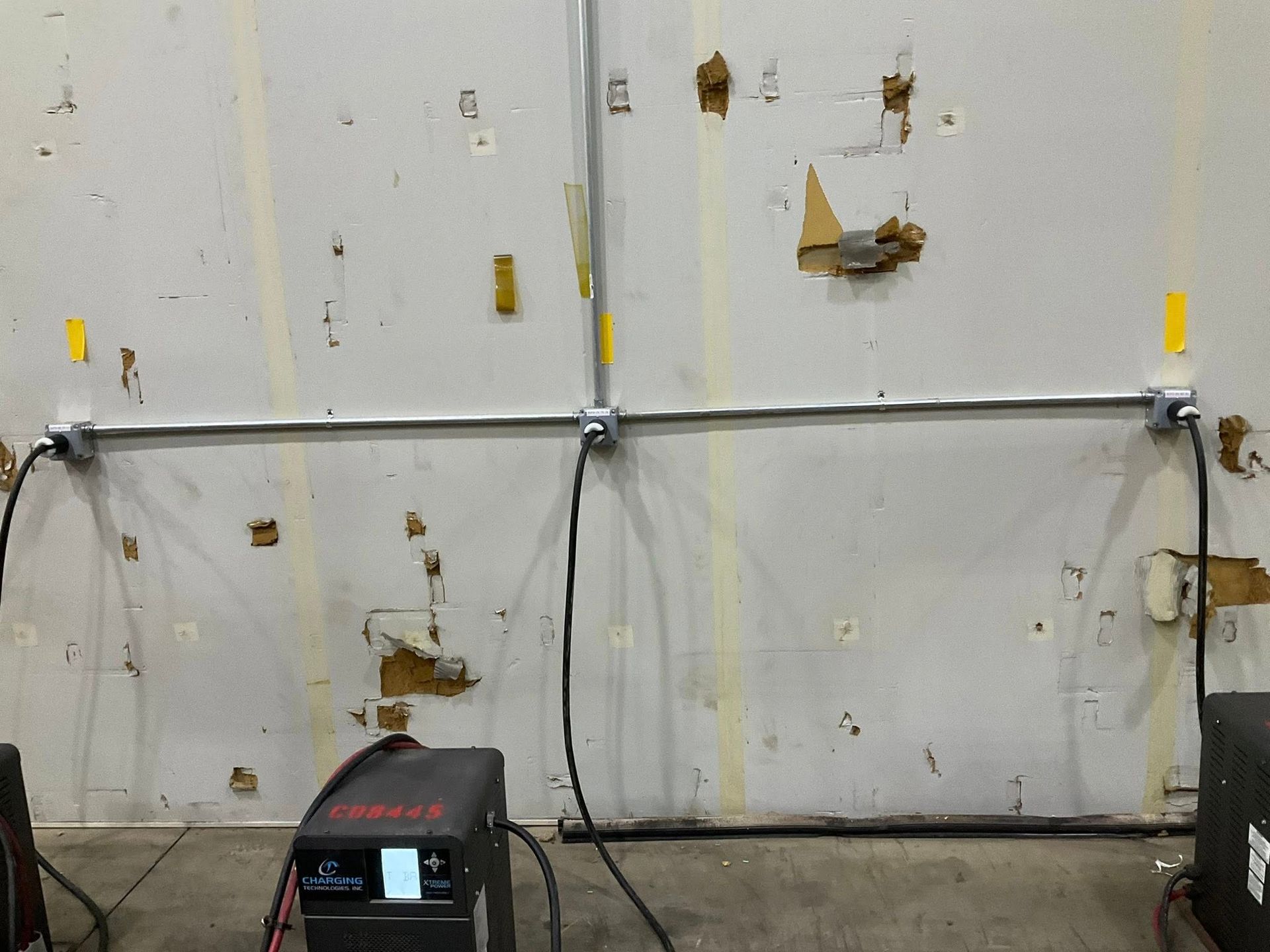Industrial wall with mounted pipes, valves, and two black floor units in a utility room