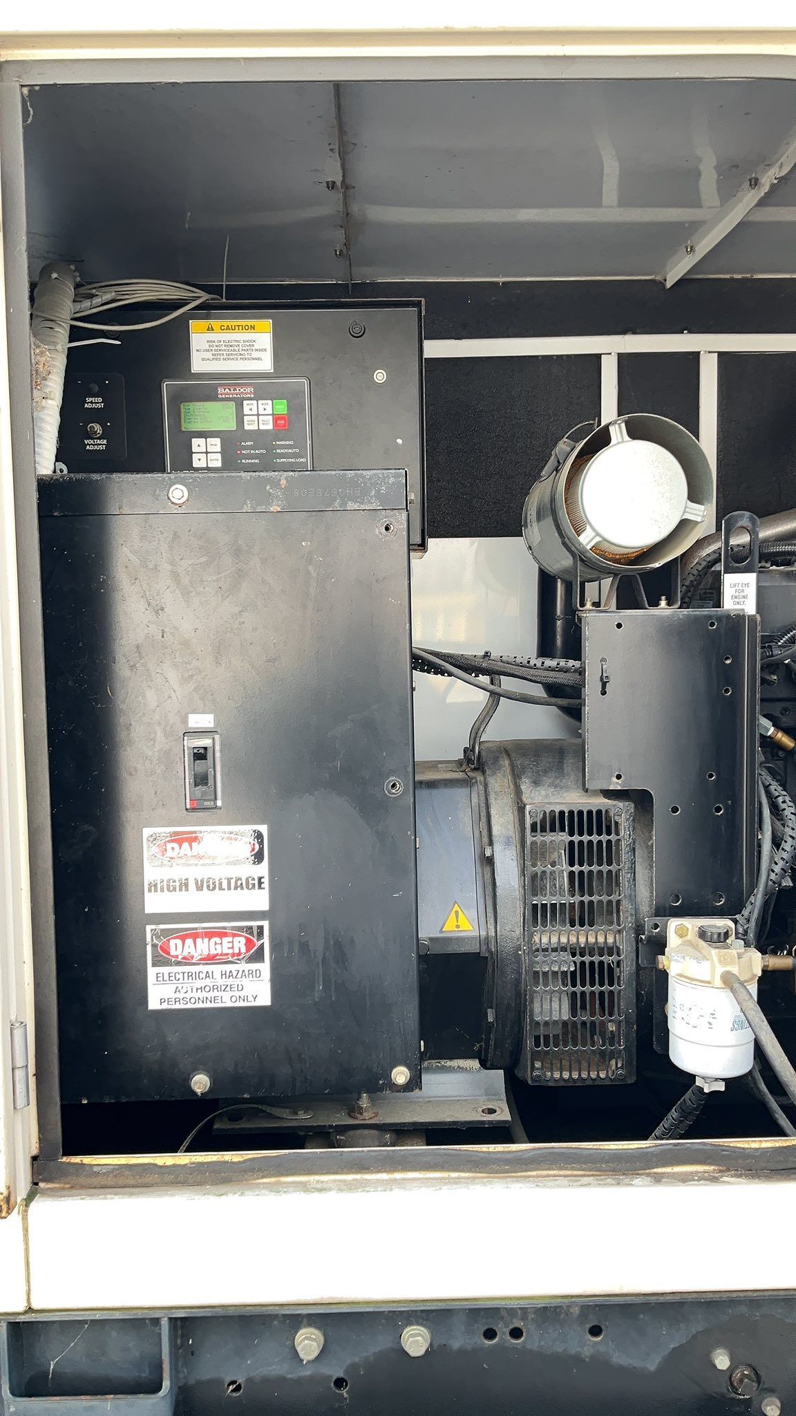 Industrial machinery inside a metal cabinet, with gauges, pipes, and warning labels.