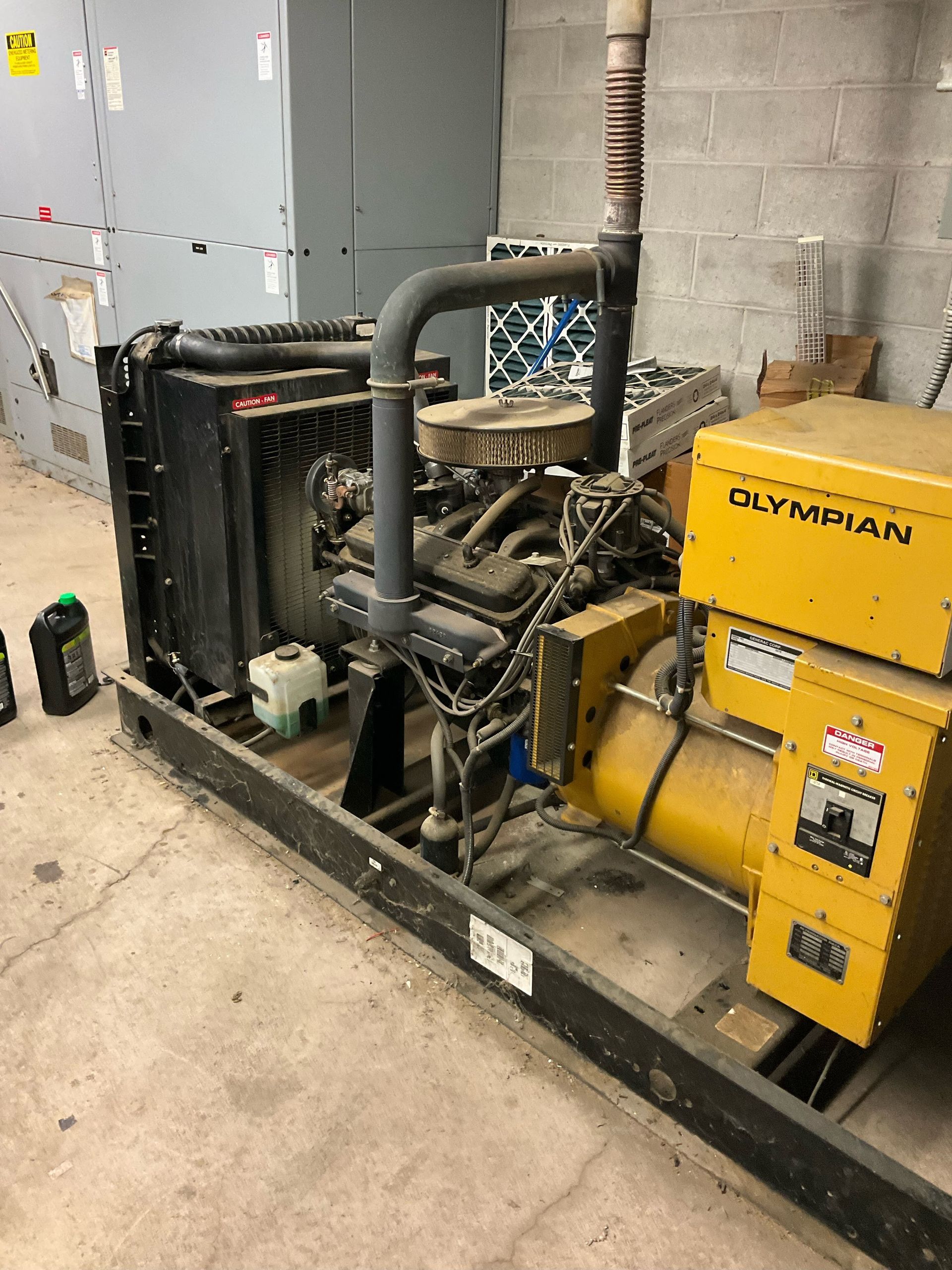 Industrial generator and pump equipment in a utility room, with yellow and black machinery and gray pipes.