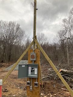 Utility meter box on a wooden post with guy wires in a wooded outdoor area
