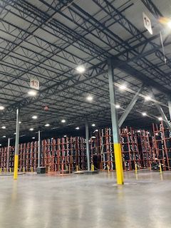 Large warehouse interior with tall metal shelving, yellow support columns, and a polished concrete floor