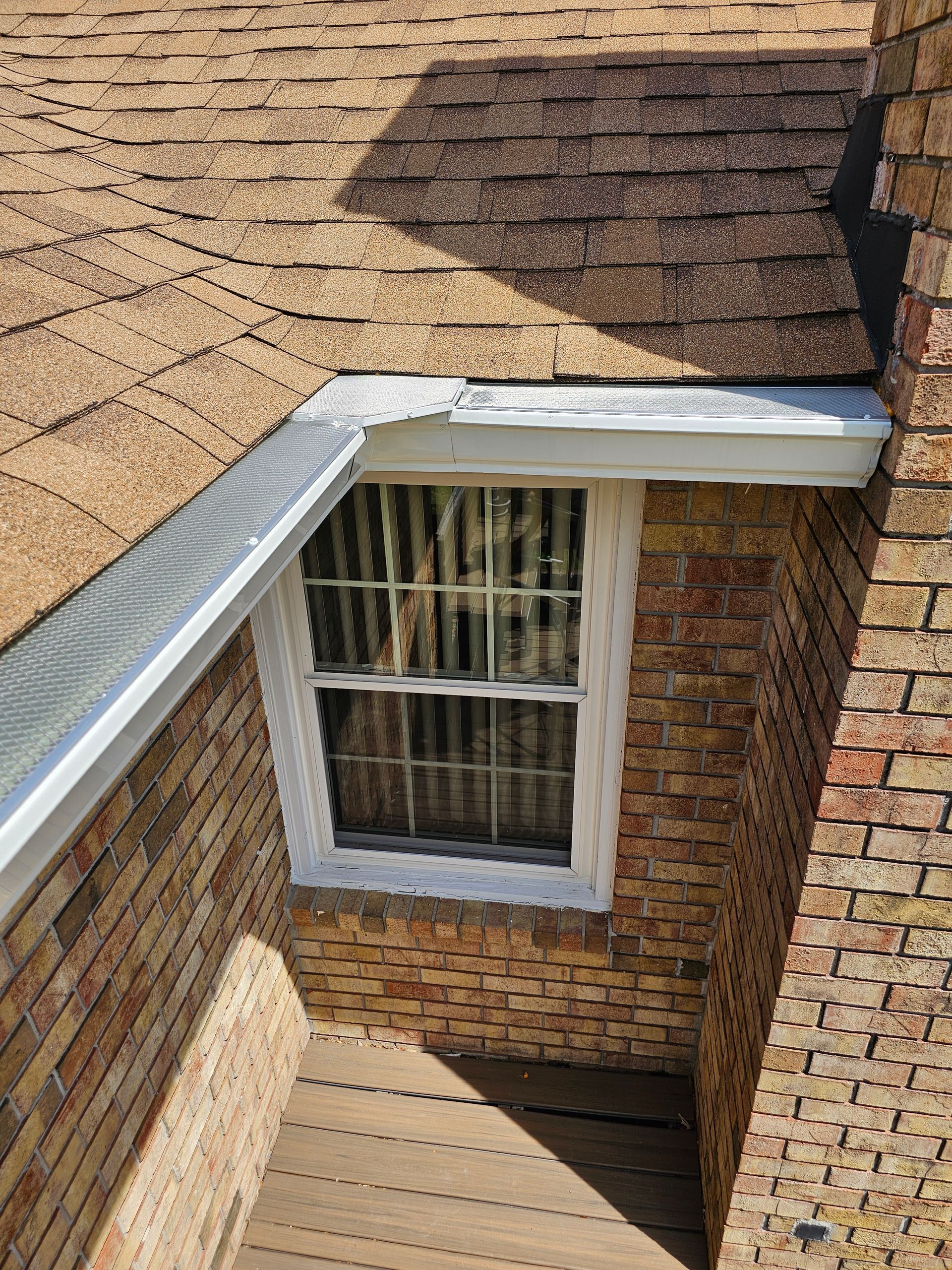 Brick wall with a window, a roof, and a gutter.