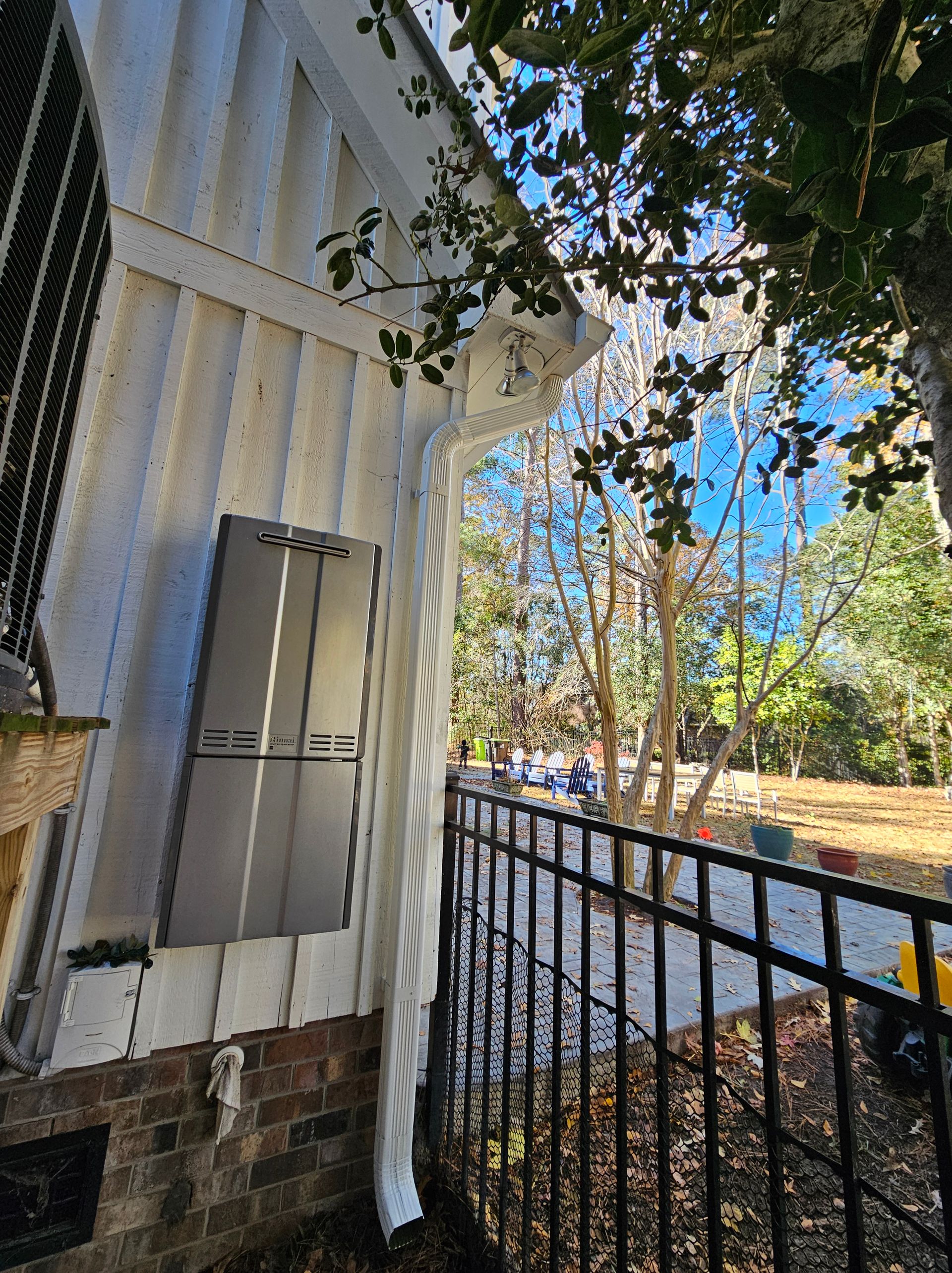 Exterior view of a white building with a black fence, trees, and blue sky in the background.