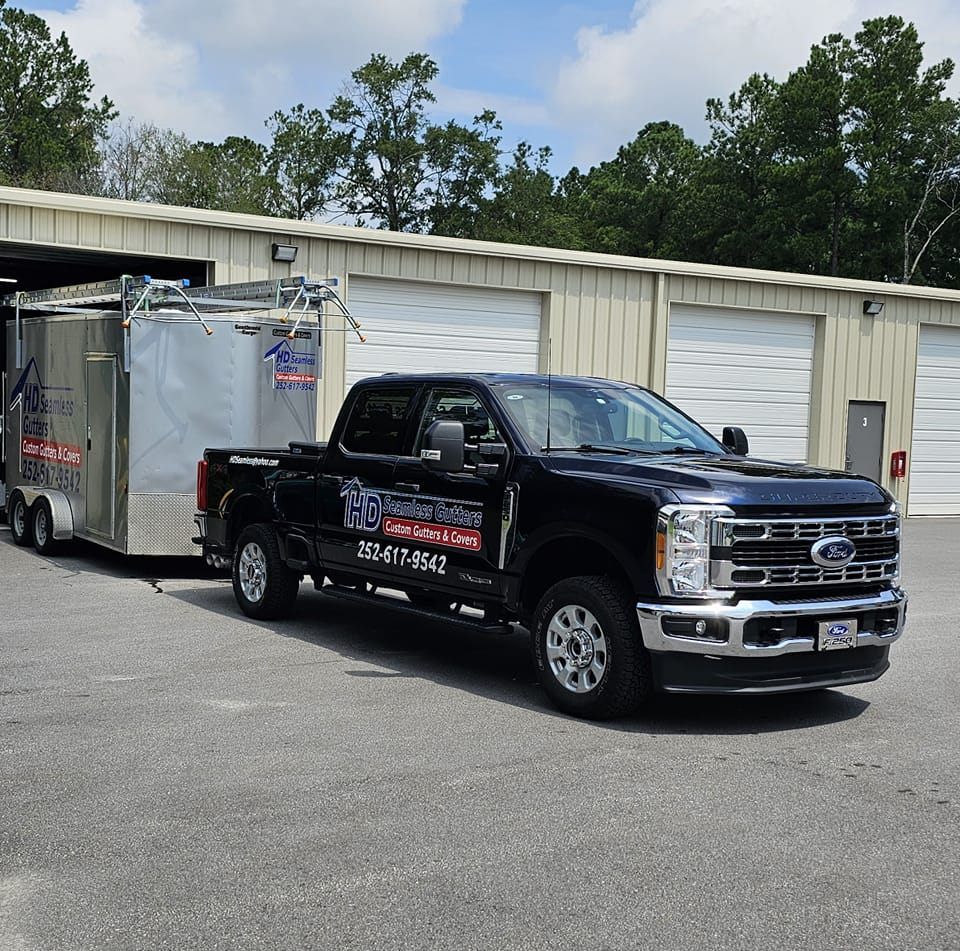 A black Ford truck towing a trailer, parked in front of a building.