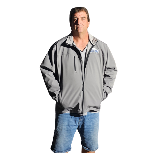 Man in gray jacket and denim shorts, hands in pockets, standing against a white backdrop.