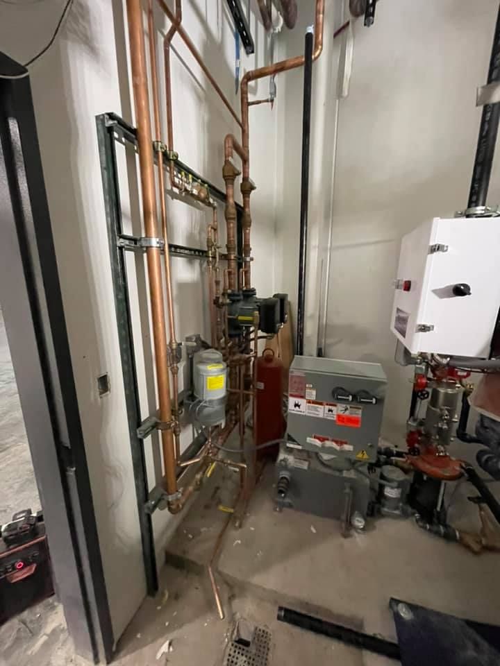 Industrial mechanical room with pipes, valves, pumps, and electrical equipment along a narrow hallway. Industrial mechanical room with pipes, valves, pumps, and electrical equipment along a narrow hallway.