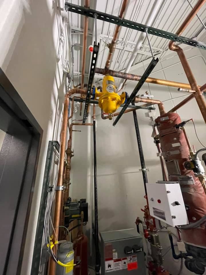 Industrial ceiling area with pipes and valves, including a yellow overhead hoist in a mechanical room Industrial ceiling area with pipes and valves, including a yellow overhead hoist in a mechanical room