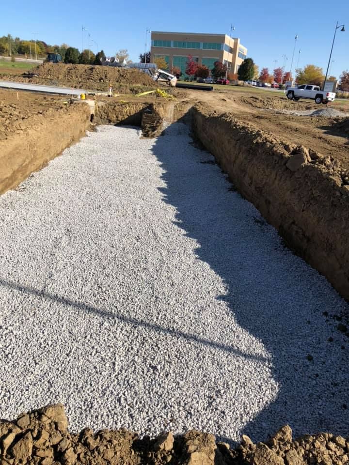 Gravel-filled trench at a construction site with a building in the distance Gravel-filled trench at a construction site with a building in the distance