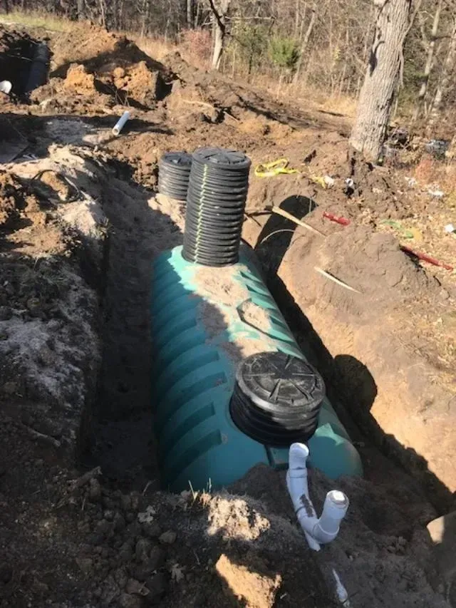Underground septic tank installation with black vent pipes and white plumbing in a dirt trench Underground septic tank installation with black vent pipes and white plumbing in a dirt trench