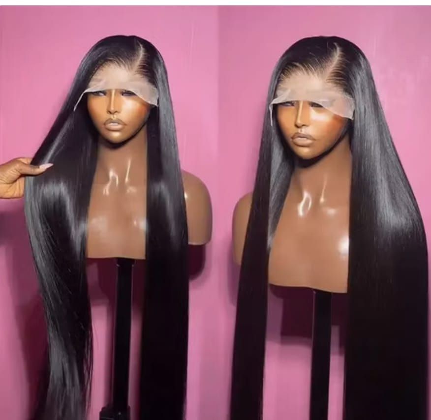 Two long straight black wigs on mannequin heads against a pink background