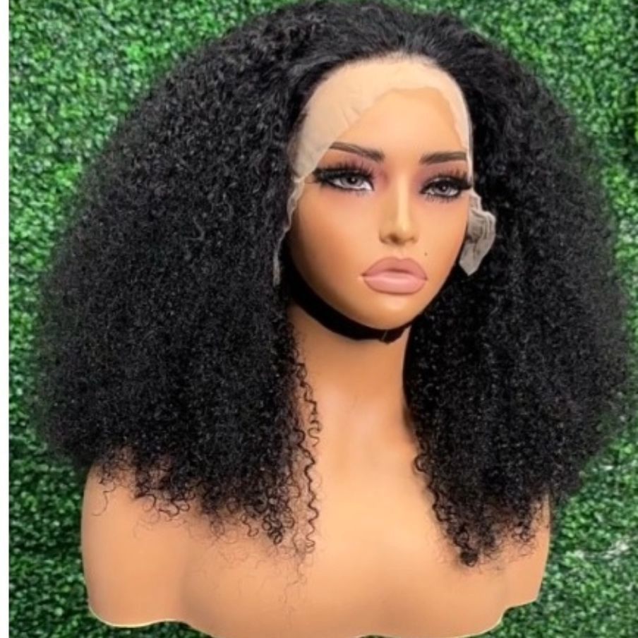 Mannequin head with voluminous curly black hair and blond roots against a green hedge background