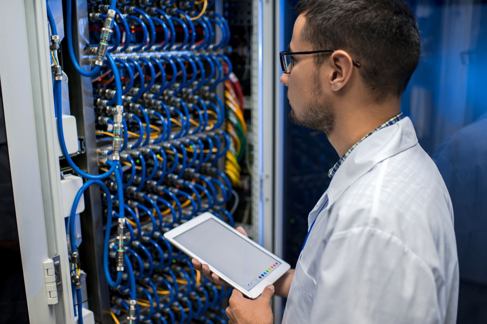 Man holding digital tablet standing by supercomputer server.