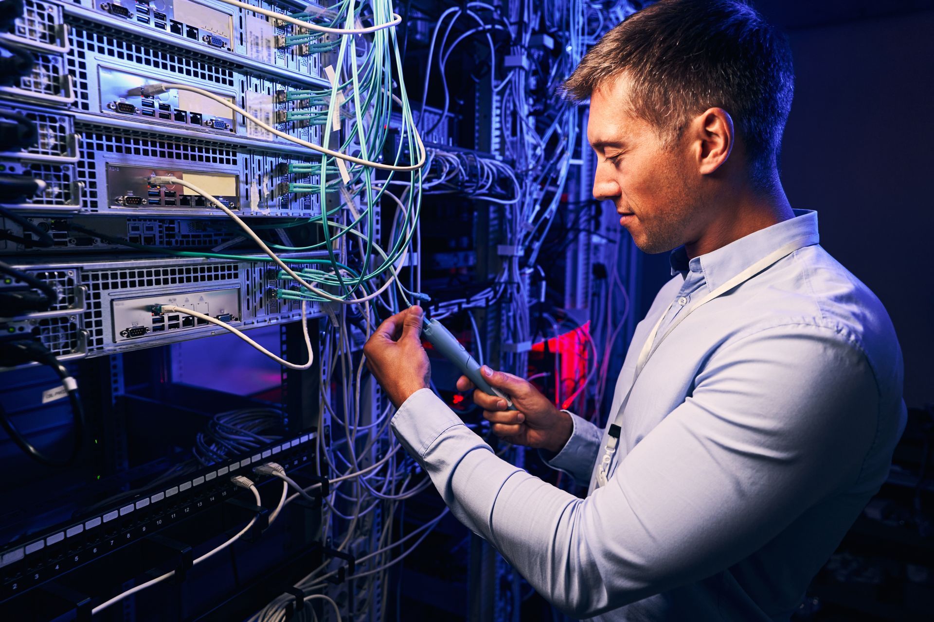 Focused data center employee checking cabling infrastructure.