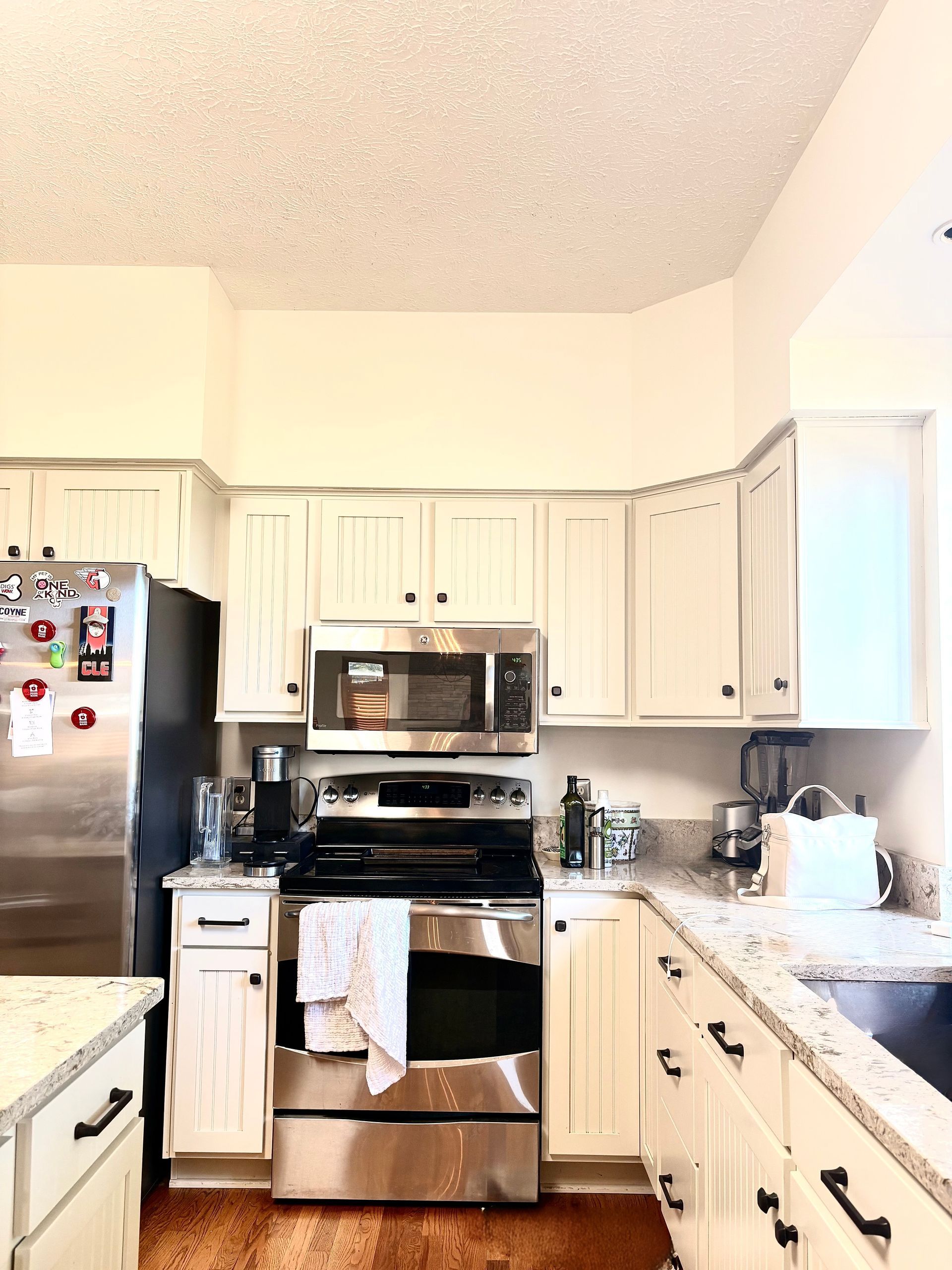White kitchen with stainless steel appliances, granite countertops, and light-colored cabinets.