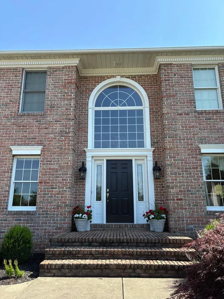 Red brick house with a dark door, arched window, and steps leading up.