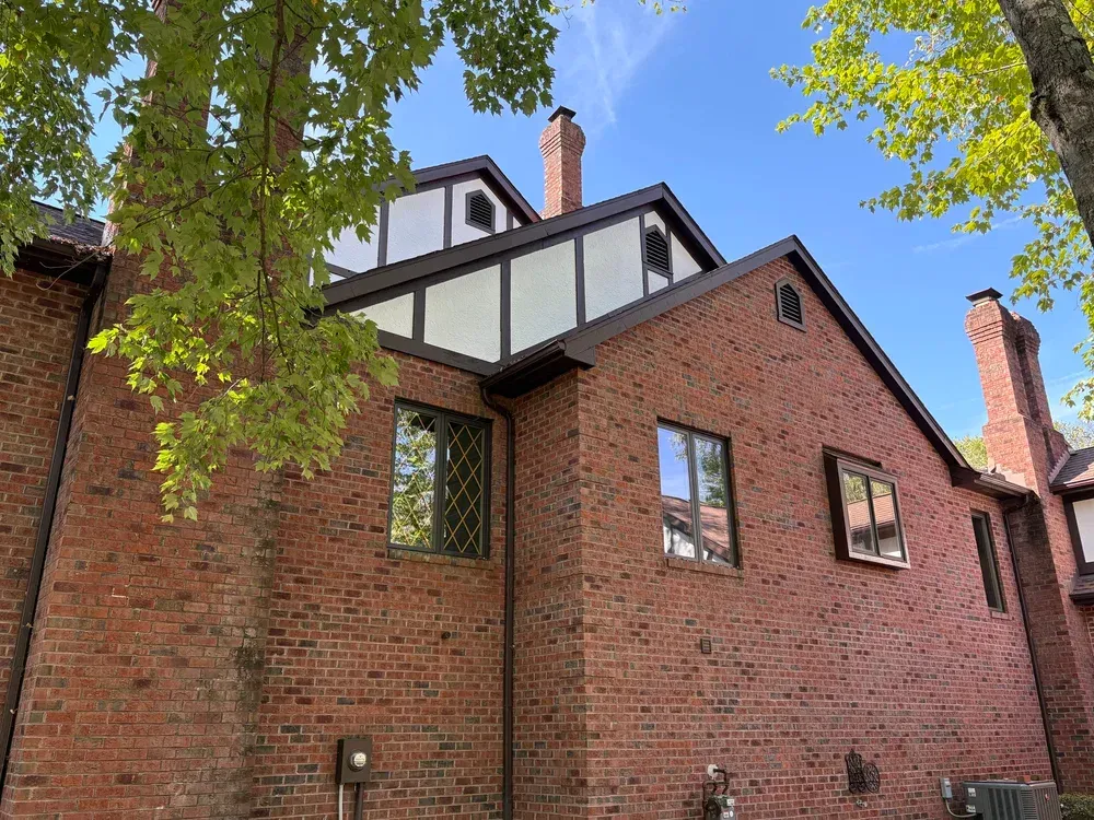 Brick building with brown trim and white Tudor-style accents under a blue sky.