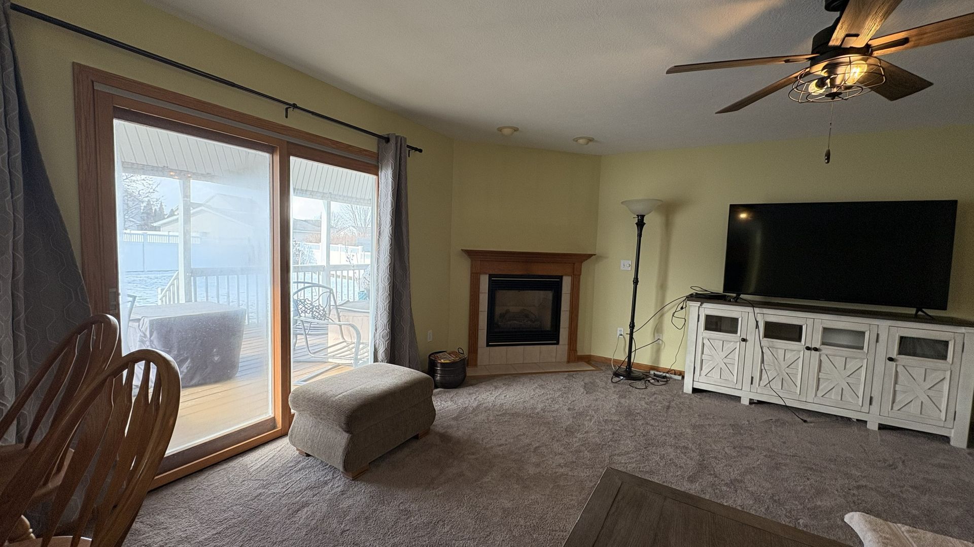 Living room with sliding glass door, fireplace, TV, and neutral-colored carpet.