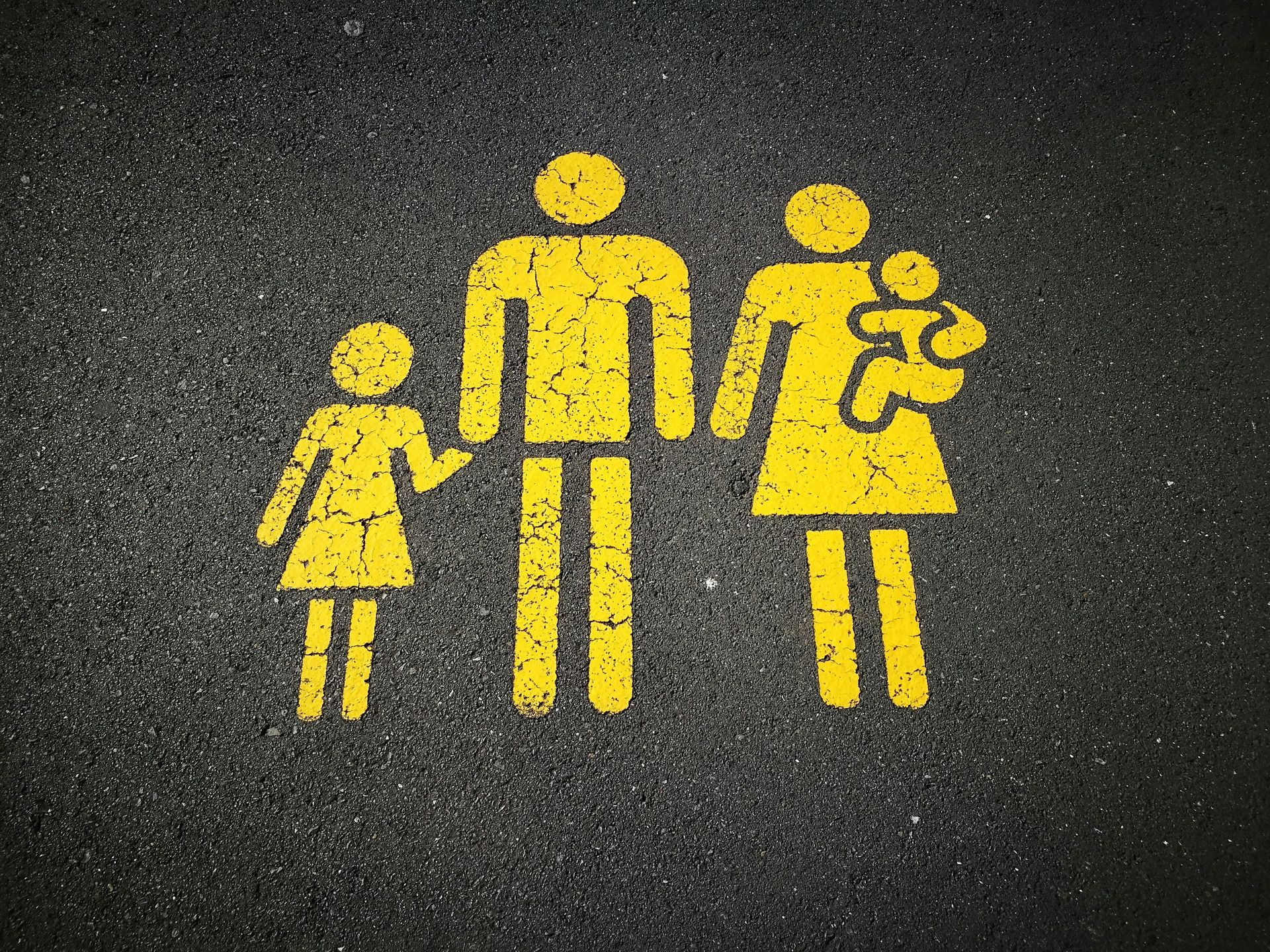 A yellow sign of a family is painted on the road.