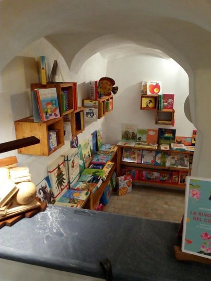 un'antica libreria con muri in pietra e scaffali con dei libri