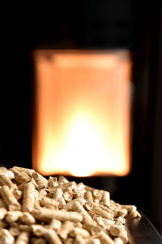 Mucchio di pellet di legno davanti a un camino ben illuminato.
