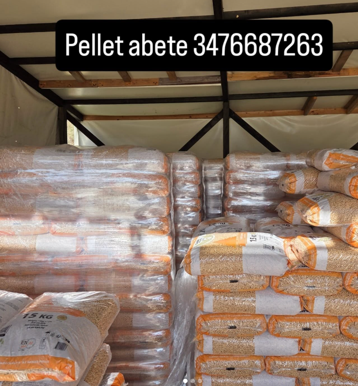 Pile di pellet di legno in sacchi, possibilmente di abete, con un numero di telefono in cima.